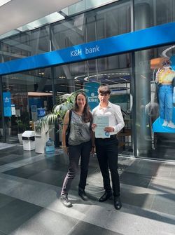 K&H bank előtt kép az oklevéllel.